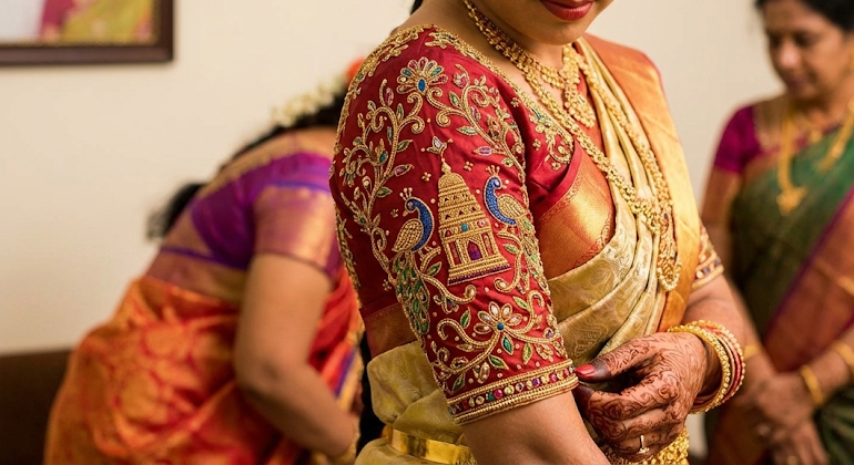 Bridal Aari work blouse with intricate temple and peacock motifs designed by the Best Aari Work Designer in Mayiladuthurai for Bridal Design
A South Indian bride wearing a richly detailed bridal Aari work blouse featuring traditional temple and peacock motifs, handcrafted by the best Aari work designer in Mayiladuthurai. This custom bridal embroidery highlights fine craftsmanship, cultural detailing, and elegant design suited for weddings and special occasions.